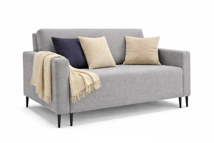 Szara sofa LAURA GERMAN z jasnymi poduszkami i kocem